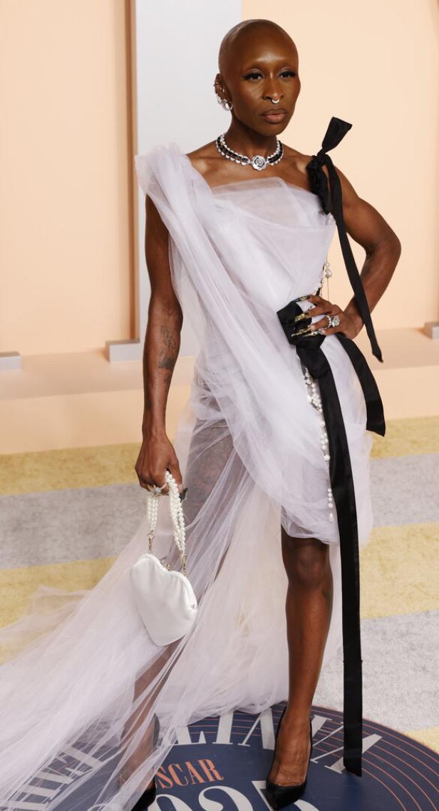 Cynthia Erivo in einem weißen Tüllkleid mit schwarzer Schleife und einer herzförmigen Handtasche.