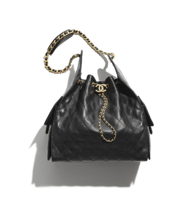 Eine schwarze Chanel Handtasche mit goldenen Ketten auf einem weißen Hintergrund.