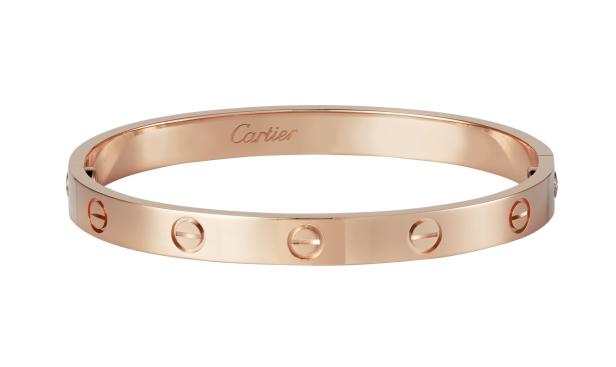 Ein roségoldenes „Love“-Armband von Cartier liegt auf einem weißen Hintergrund.