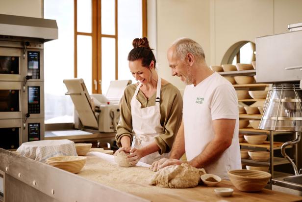 Eine Frau und ein Mann kneten Teig in einer Bäckerei.