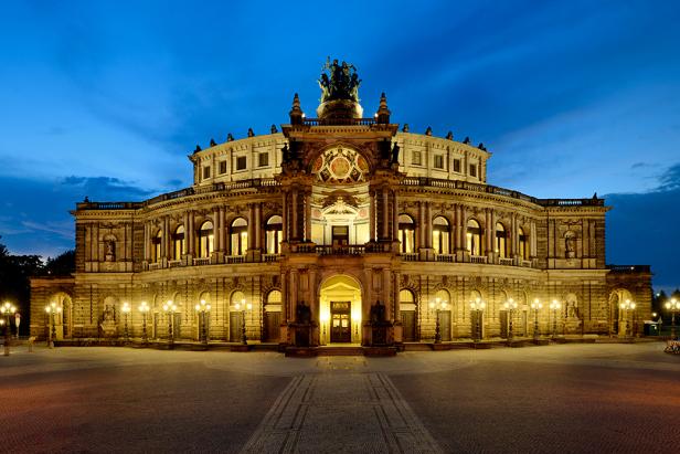 Ein barockes Gebäude von außen, das nachts beleuchtet wird.