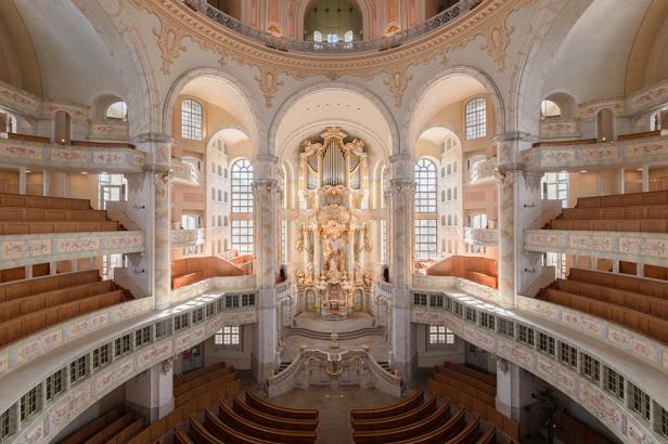 Eine weiße Kirche von innen, mit vielen Holz-Sitzbänken.