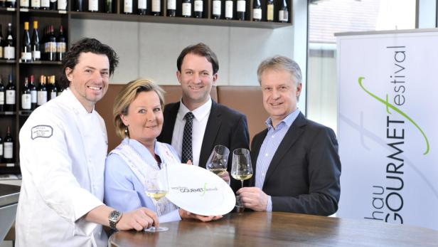 Eine Gruppe von Personen posiert mit Weingläsern und einem Teller für das Wachau Gourmetfestival.