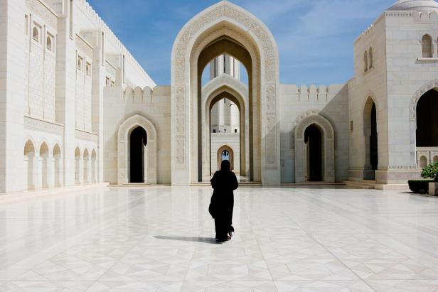 Eine Frau in traditioneller Kleidung geht auf den Sultan-Qabus-Moschee zu.