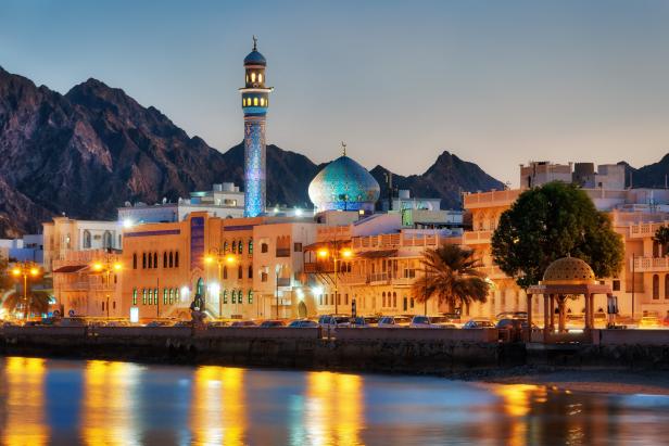 Blick auf Maskat, Oman, mit Moschee und Bergen im Hintergrund.