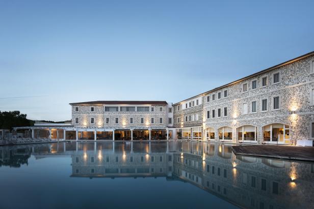Ein großes Hotel mit Pool spiegelt sich im Wasser.
