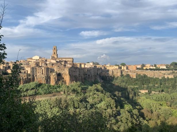 Die Stadt Pitigliano in Italien thront auf einem Felsen über grüner Vegetation.