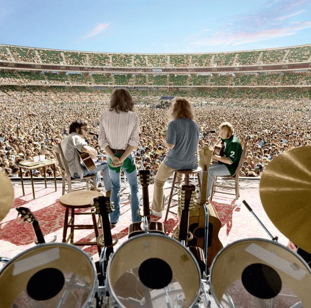 Eine Band spielt vor einer riesigen Menschenmenge in einem Stadion.