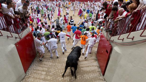 Ein Stier rennt durch eine Menschenmenge beim Stierlauf von Pamplona.