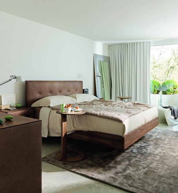 Ein Schlafzimmer mit einem Holzbett und beigen Textilien.