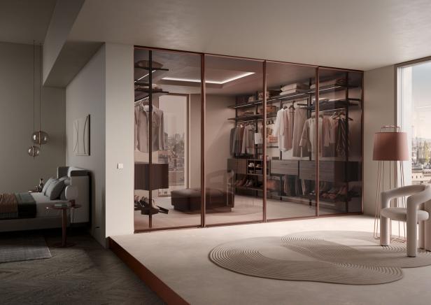 Ein begehbarer Kleiderschrank mit Glasfronten in einem modernen Schlafzimmer.