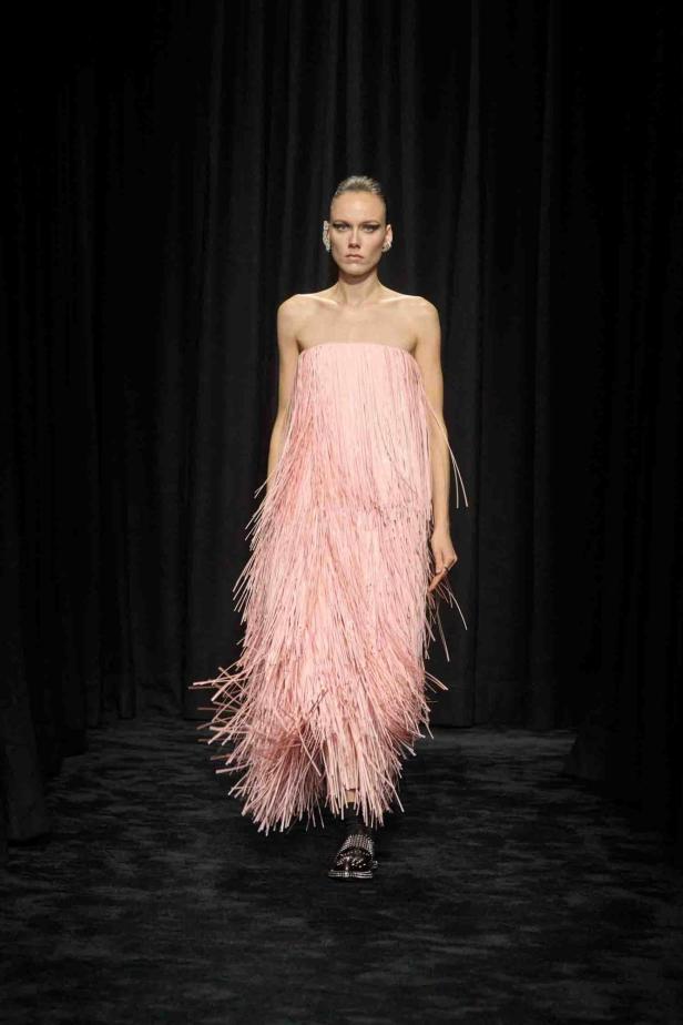 Eine Frau trägt ein trägerloses, rosa Kleid mit Fransen auf einem Laufsteg.