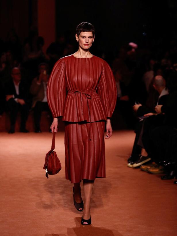 Ein Model präsentiert ein rotes Lederensemble auf dem Laufsteg.