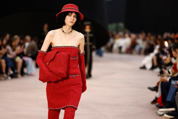 Ein Model in einem roten Chanel-Kleid und Hut auf dem Laufsteg.