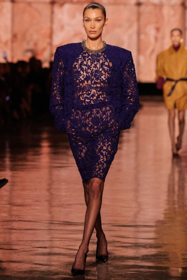Bella Hadid läuft in einem blauen Spitzenkleid über einen Laufsteg.
