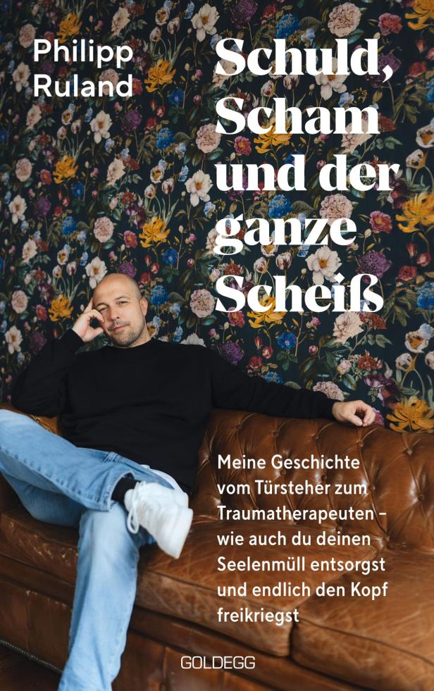 Das Buch „Schuld, Scham und der ganze Scheiß“ von Philipp Ruland liegt auf einem Sofa.