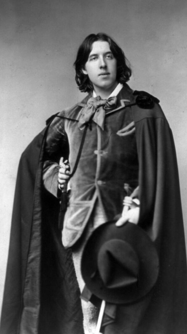 Oscar Wilde posiert im wallenden Mantel für ein Foto.