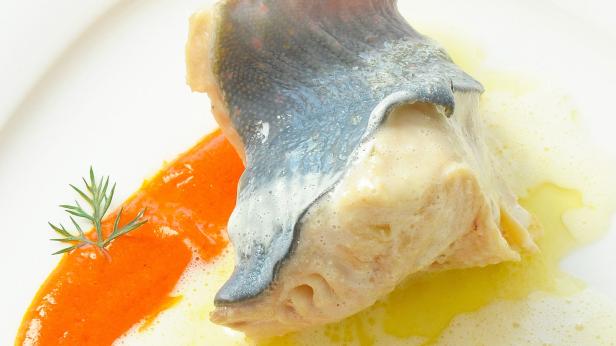 Ein Stück eingelegter Hering mit Dill auf einem Teller angerichtet.