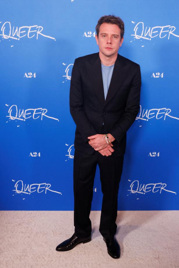 Anton Yelchin posiert vor einer Wand mit dem Schriftzug „Queer“.