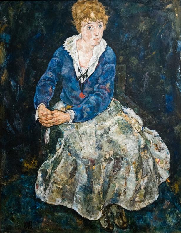Ein Gemälde einer sitzenden Frau in einem blauen Oberteil und einem weiten Rock vor dunklem Hintergrund.