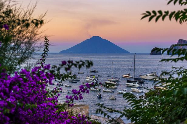 Blick auf das Meer mit Booten und der Insel Stromboli im Hintergrund.