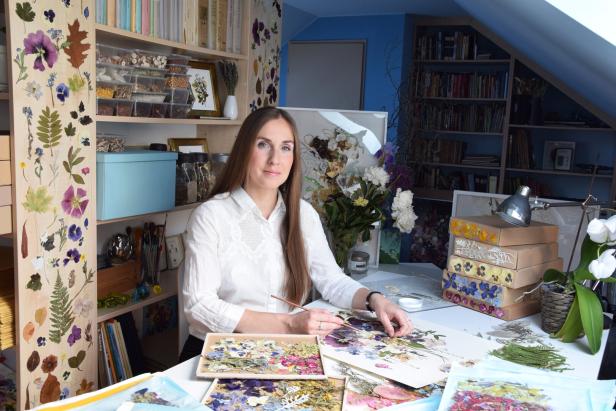 Eine Frau arbeitet in ihrem Atelier mit getrockneten Blumen und Pflanzen.