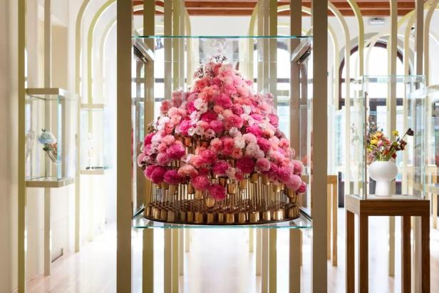 Eine pyramidenförmige Anordnung aus rosa und weißen Nelken in einem gläsernen Schaukasten.
