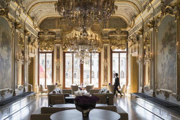 Ein prunkvoller Salon mit Kronleuchtern und einer Person, die durch den Raum geht.