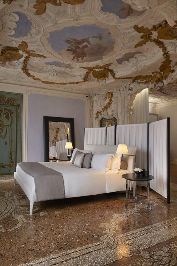 Ein Schlafzimmer mit einem großen Bett und einer kunstvollen Deckenmalerei.