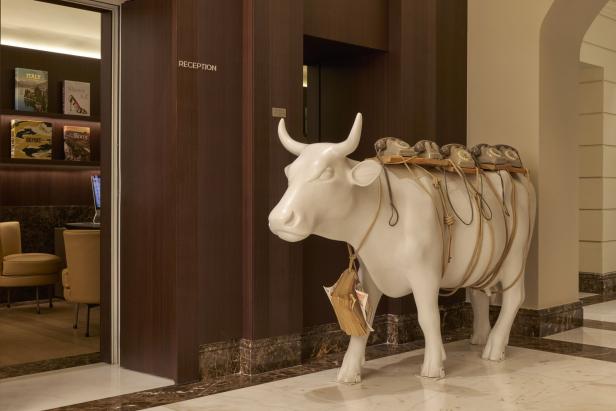 Eine weiße Kuhskulptur trägt Telefone auf dem Rücken in einem Hotel neben der Rezeption.