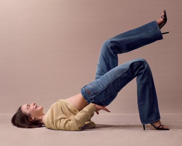 Eine Frau liegt auf dem Boden und trägt Jeans und hochhackige Schuhe.