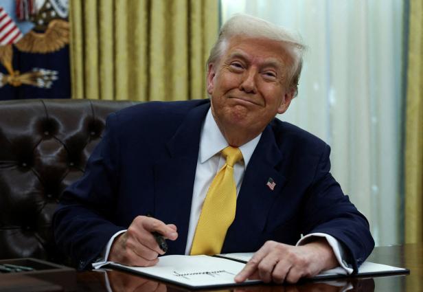 FILE PHOTO: U.S. President Donald Trump signs an executive order in the Oval Office of the White House in Washington Zufriedender Donald Trump