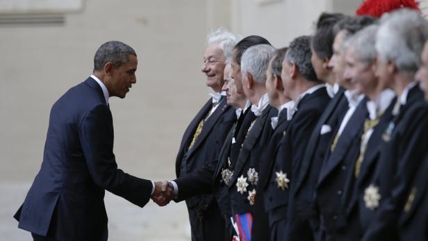 Barack Obama schüttelt einer Gruppe formell gekleideter Männer die Hand.