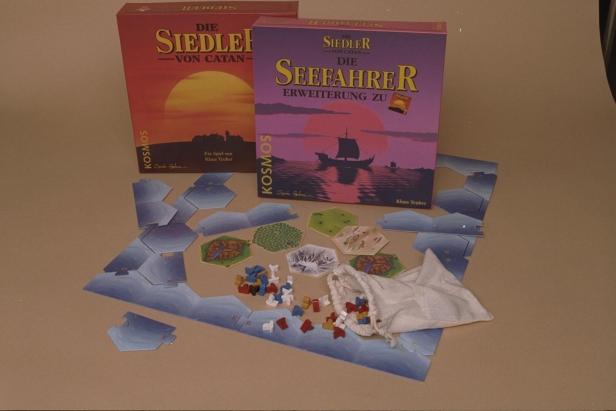 Spielmaterial und Schachteln für „Die Siedler von Catan“ und die Erweiterung „Seefahrer“.