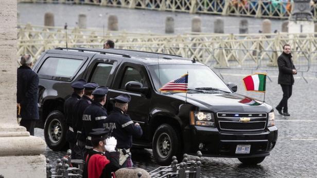 Eine schwarze Limousine mit amerikanischer und italienischer Flagge vor dem Vatikan.