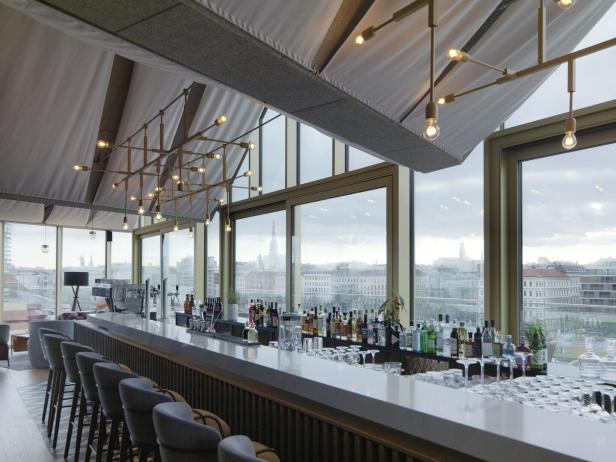 Eine Bar mit Blick auf die Stadt durch große Fenster.