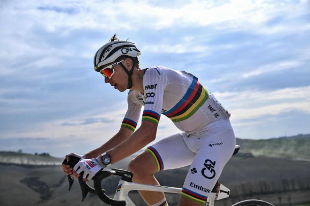 Ein Radrennfahrer in weißer Rennbekleidung und Helm fährt auf einer Straße.