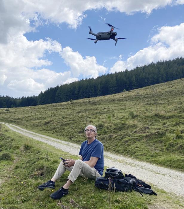 Ein Mann steuert eine Drohne in einer ländlichen Gegend.