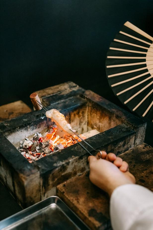 Eine Garnele wird über glühenden Kohlen gegrillt.