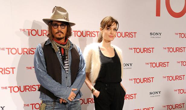 Angelina Jolie und Johnny Depp posieren vor einem Werbeplakat für den Film „The Tourist“.