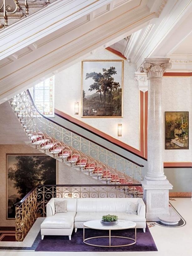 Ein elegantes Treppenhaus mit Kunstwerken und einem weißen Sofa im Vordergrund.