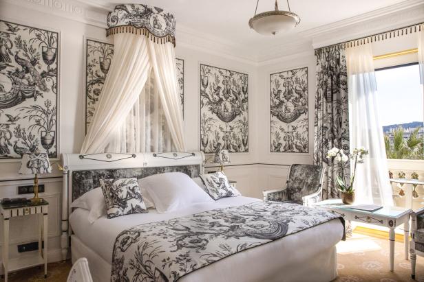 Ein Schlafzimmer mit Himmelbett und schwarz-weiß gemusterten Tapeten.
