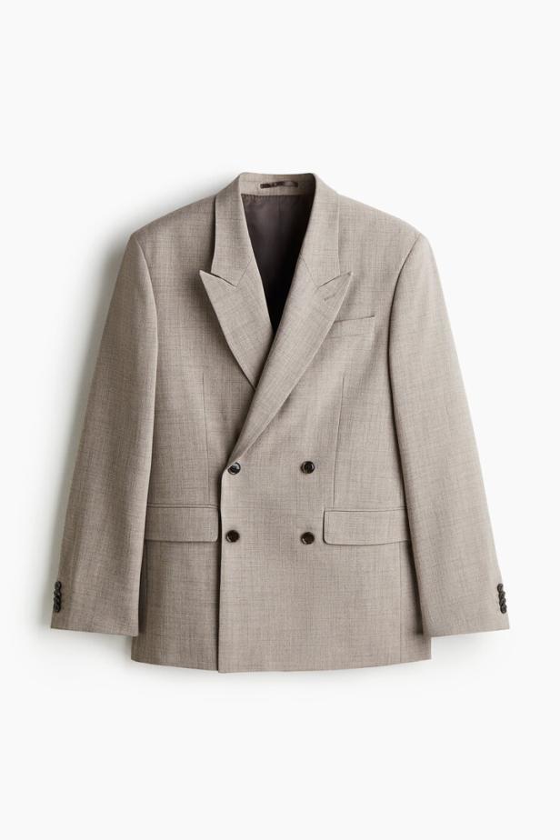 Ein hellbrauner, zweireihiger Blazer hängt vor einem weißen Hintergrund.