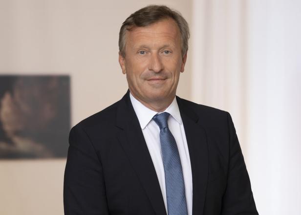 Ein Mann mit Anzug und Krawatte blickt freundlich in die Kamera.