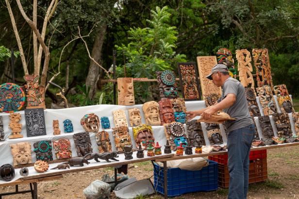 Entlang breiter Kieselstein-Wege drapiert ein Händler Souvenirs auf seinem Verkaufsstand in Chichén Itzá.
