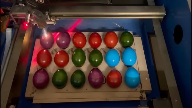 Ein Laser bearbeitet eine Reihe von bemalten Ostereiern.