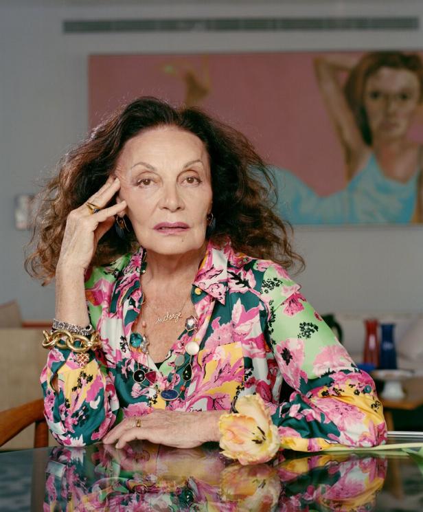 Diane von Fürstenberg posiert in einem farbenfrohen Hemd mit Blumenmuster vor einem Gemälde.