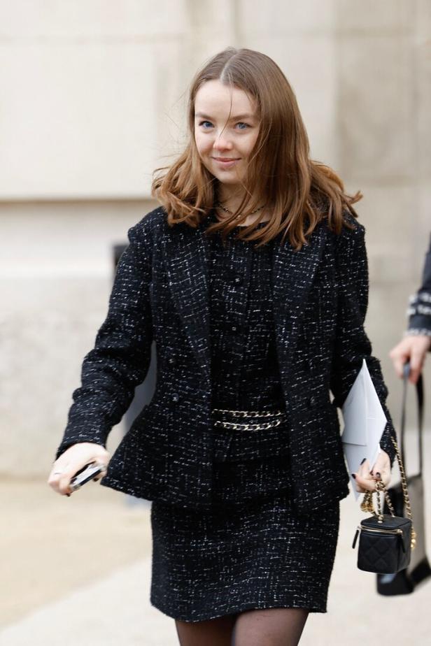 Eine Frau in einem schwarzen Tweed-Kostüm mit einer kleinen Handtasche.