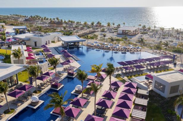 Luftaufnahme eines Luxusresorts mit Pools, Sonnenschirmen und Blick auf das Meer.
