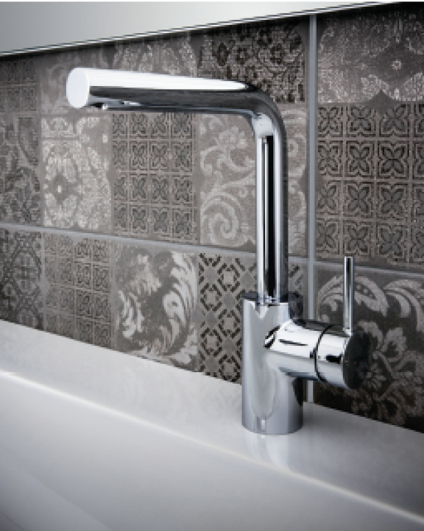 Ein glänzender, moderner Wasserhahn vor einer Wand mit gemusterten Fliesen.